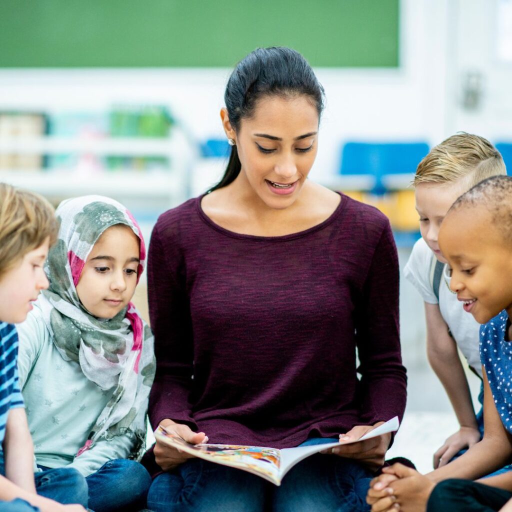 preschool teacher reading with four children in a classroom