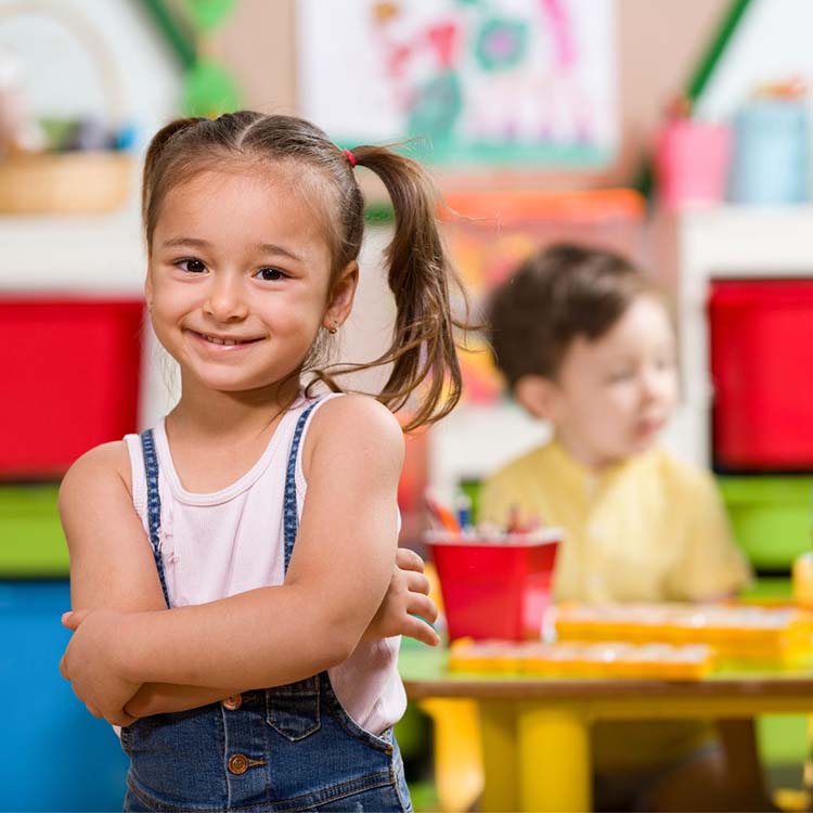 smiling child in preschool with classmates in the background